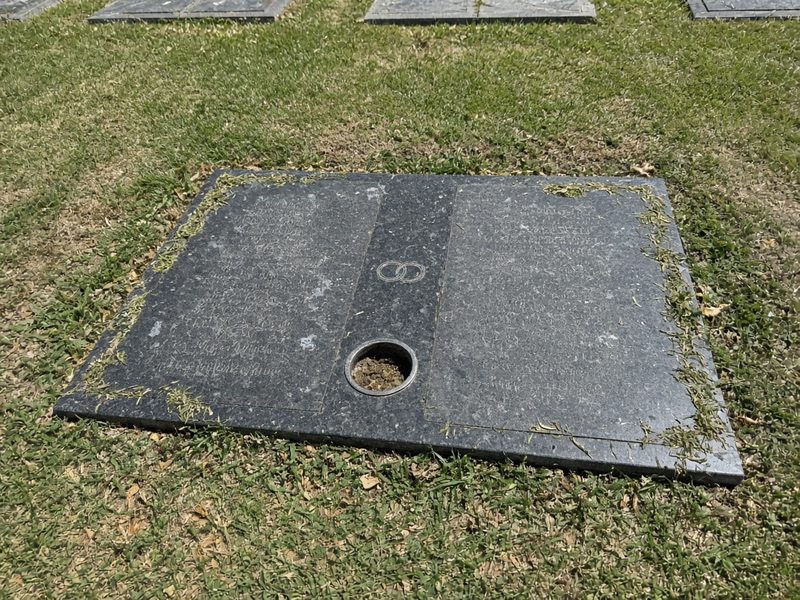 Illustrative example, before: a double companion marker for a couple, dusty with water spots and grass over its edges, with an empty vase